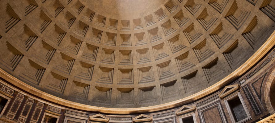 A large beam of light coming from the oculus illuminates the ceiling pattern of the Pantheon in Rome.